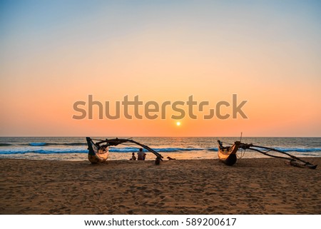 Young man and boy, father and son, dog sitting on the beach at sunset, Kalutara, Sri Lanka