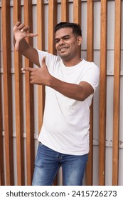 Young man with braces gesturing frame with fingers