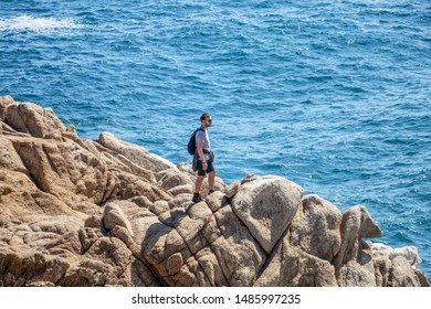 Young man brave hiker standing on the rocky coast of Pacific Ocean - Powered by Shutterstock