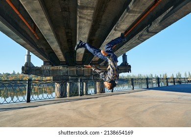 Young man break dancer doing somersault acrobatic stunts dancing on urban background. Street artist breakdancing outdoors