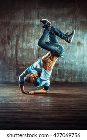 Young man break dancing on old wall background. Vintage film style colors. - Shutterstock ID 427069756
