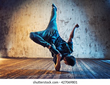 Young man break dancing on wall background. Blue and red lights effect.