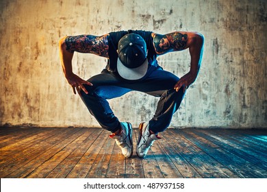 Young man break dancing on wall background. Blue and yellow colors tint. Tattoo on body. - Shutterstock ID 487937158
