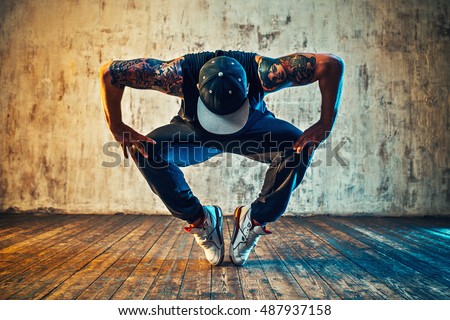 Young man break dancing on wall background. Blue and yellow colors tint. Tattoo on body.