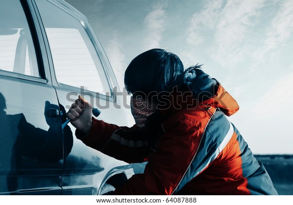Young man breaking door of a\
car