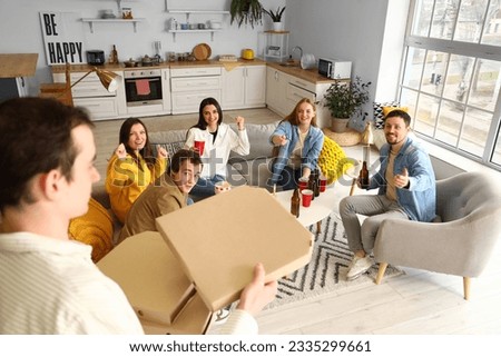 Young man bringing tasty pizza to his friends at home
