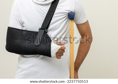Young man broken arm and leg on isolated. Man put on plaster cast splint with walking sticks crutches. Patient wearing sling support arm with neck collar. life insurance and accident