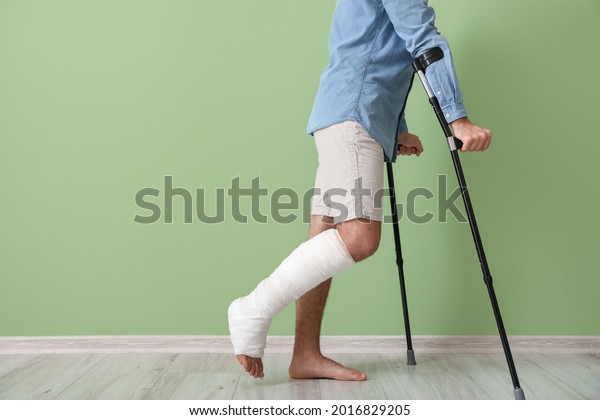 Young man with broken\
leg near color wall