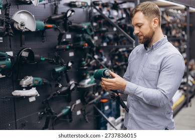 Young man is browsing construction tools at a DIY equipment store, carefully inspecting a heat gun as he plans his next home improvement project