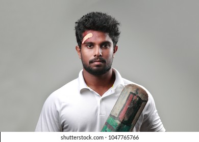 Young Man With A Bruised Forehead Holding Cricket Bat 