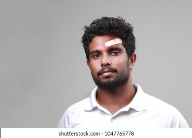 Young Man With A Bruised Forehead Holding Cricket Bat 