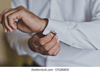 Young man buttoning the cuff links on the sleeves.