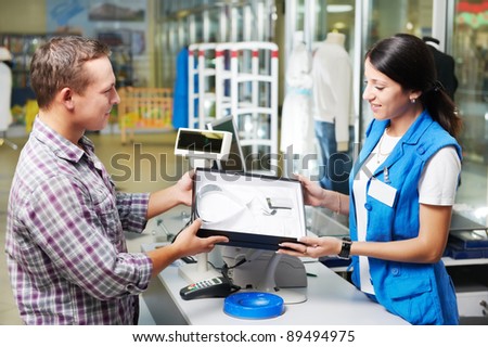 Young man buying business shirt with shop assisant at cash desk in store