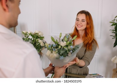 Young Man Buying Flowers In A Flower Shop From A Seller