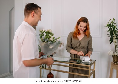 Young Man Buying Flowers In A Flower Shop From A Seller