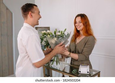 Young Man Buying Flowers In A Flower Shop From A Seller