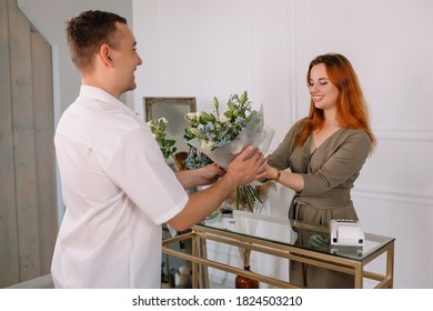 Young Man Buying Flowers In A Flower Shop From A Seller