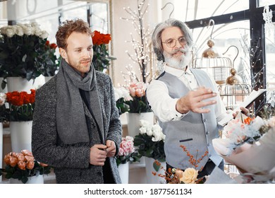 Young Man Buying Flowers. Manager Help A Client. Guy In A Gray Coat.