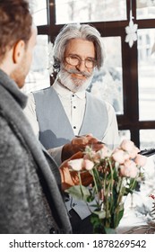 Young Man Buying Flowers. Manager Help A Client. Guy In A Gray Coat.