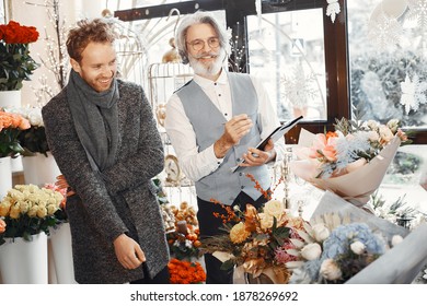 Young Man Buying Flowers. Manager Help A Client. Guy In A Gray Coat.