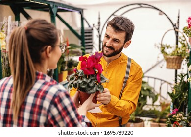 Young Man Buying Flowers From Nursery Garden Female Worker.