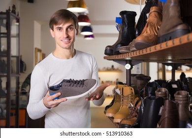 Young Man Buying Summer Shoes In A Shoe Store