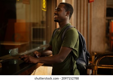 Young man buying a ticket for train with a credit card. Handsome smiling man going to a trip.	