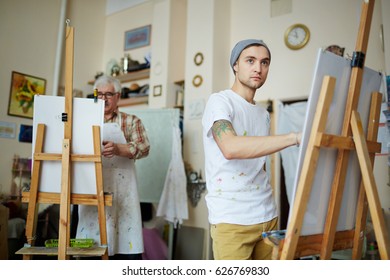 Young Man By Easel Drawing From Life In Workroom