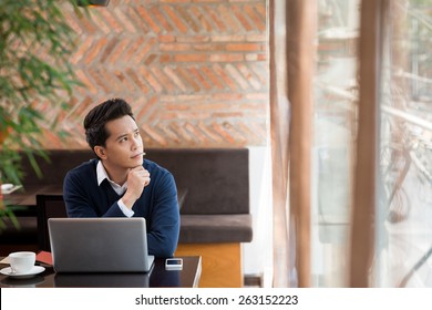 Young Man In A Cafe Thinking Over Idea For The New Blog Post