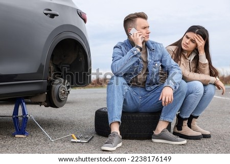 Young man calling to car service on roadside. Tire puncture