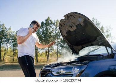 A Young Man Calls The Evacuation Service Because Her Car Is Broken And There Is Smoke Coming From Under The Hood Of The Car. Concept Road Accident.