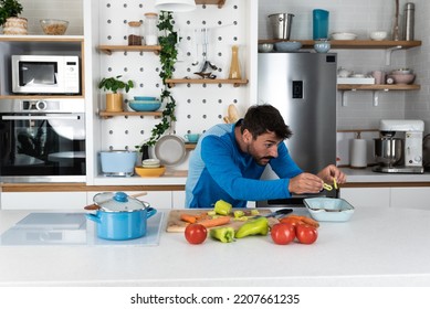 Young Man Cancer Survivor Cooking And Preparing Vegetarian Meal After Long Heavy Sickness. Vegan Male In The Kitchen Making Healthy Lunch From Fresh Vegetables Changing His Way Of Life After Illness.