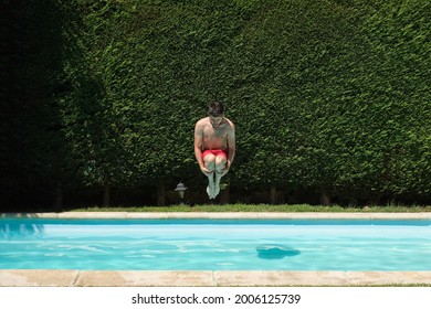 Young Man Cannonball Jumping Into A Swimming Pool. Summer Concept.