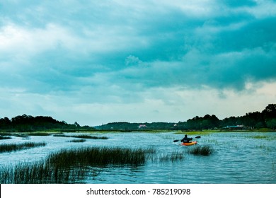 a young man canoeing in the flooded marsh of charleston, south carolina