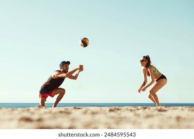 Young man in cap and shorts serves ball as young woman in bikini and sunglasses gets ready to hit ball in response. Beach volleyball in summer morning. Sport, summer, nature, active lifestyle concept - Powered by Shutterstock