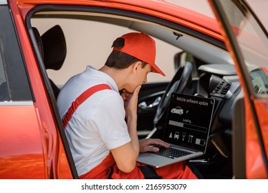 Young Man Car Mechanic Is Using An Laptop Computer To Check Diagnostic The Car Errors And Problems And Update The Car Software.
