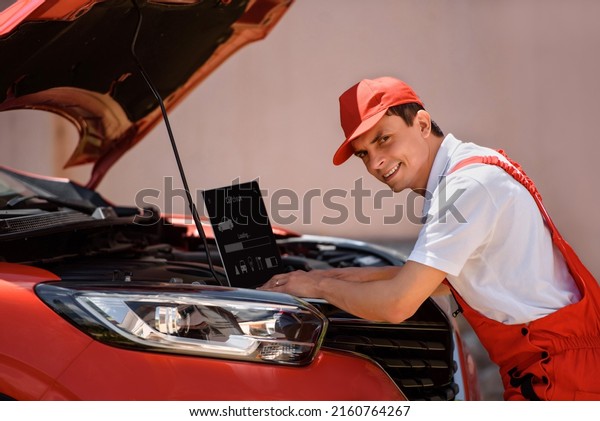 Young man car\
mechanic is using an laptop computer to check diagnostic the car\
errors and problems and fix it.\
\
