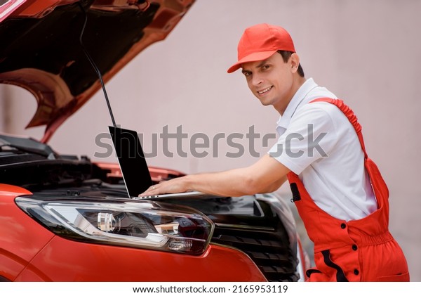 Young man car\
mechanic is using an laptop computer to check diagnostic the car\
errors and problems and fix it.\
\

