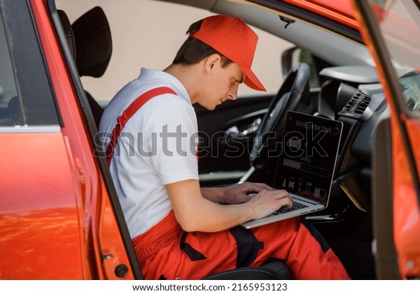 Young\
man car mechanic is using an laptop computer to check diagnostic\
the gearbox car errors and problems and fix it.\
\
