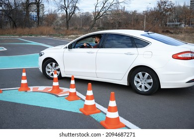 Young Man In Car On Test Track With Traffic Cones. Driving School