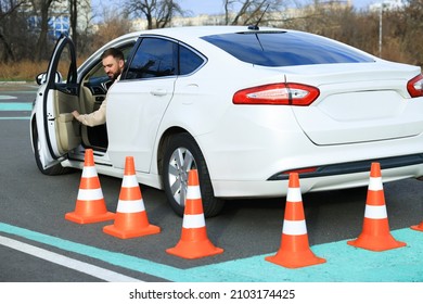 Young Man In Car On Test Track With Traffic Cones. Driving School