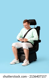 Young Man In Car Seat And With Phone On Color Background