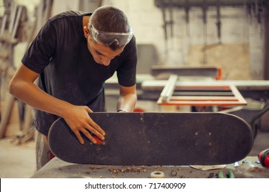 Young man in carpentry workshop fixing wheel on his skateboard. Close up - Powered by Shutterstock