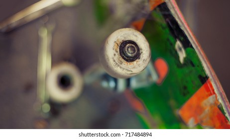 Young man in carpentry workshop fixing wheel on his skateboard. Close up