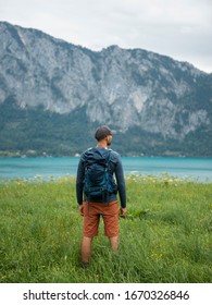 
Young man carrying backpack while hiking in mountains and enjoying scenic view