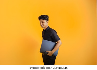 Young Man Carrying Laptop While Standing Straight
