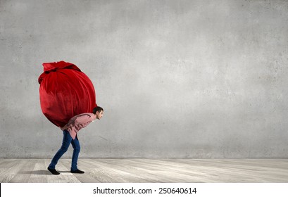 Young Man In Casual Carrying Heavy Red Bag