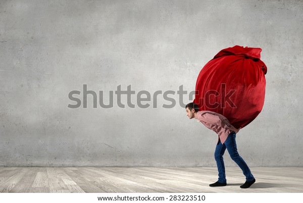 Young man in casual\
carrying heavy red bag