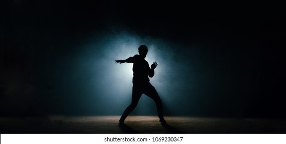 young man in casual clothers showing his dance on the dark street. night show. night dance. dansing pose