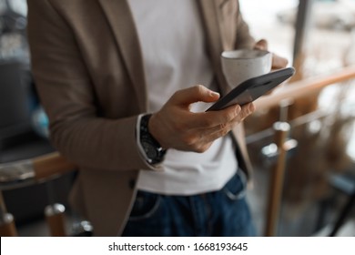 young man in casual fashion clothes holding smart phone and texting message, sms, close up cropped photo. guy searching wi-fi connection, internet
